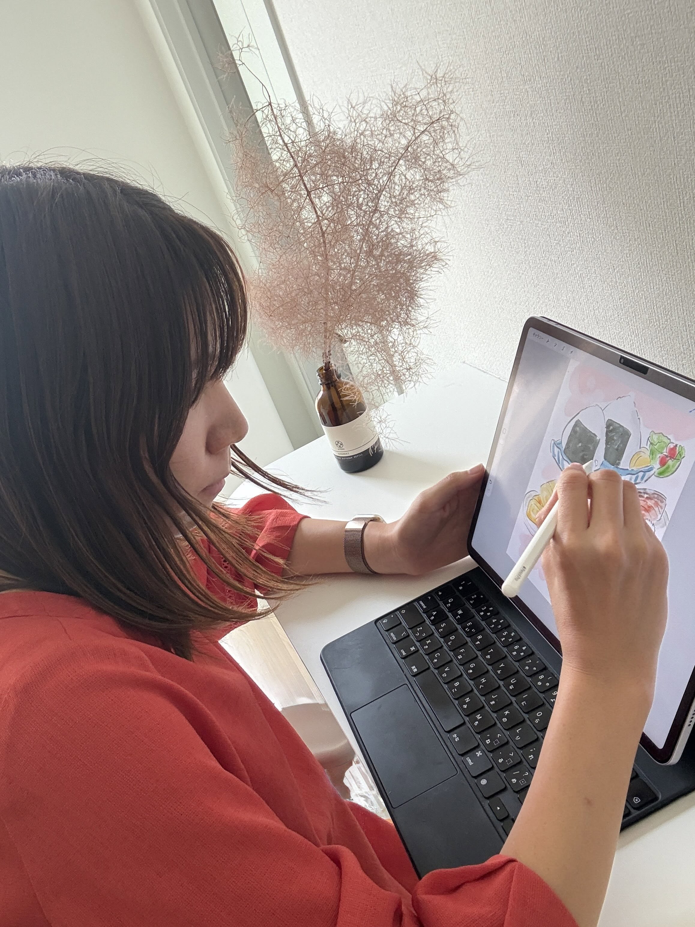 赤い服でタブレットに絵を描くやまみの横顔